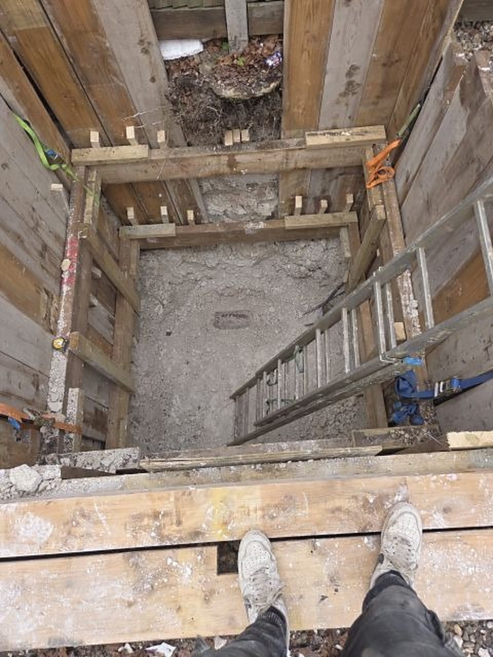 Looking down a timbered shaft with a ladder to the base
